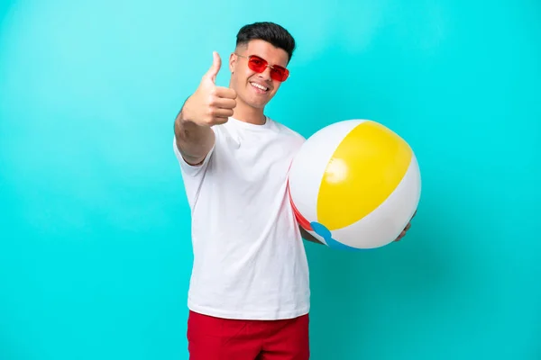 Young Caucasian Man Holding Beach Ball Isolated Blue Background Thumbs — Stockfoto