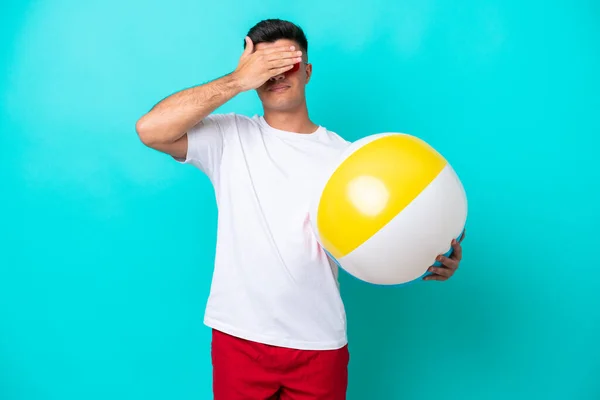 Young Caucasian Man Holding Beach Ball Isolated Blue Background Covering — 스톡 사진