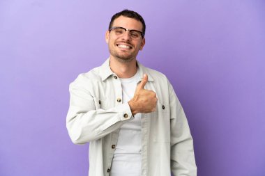 Mor arka planda kalan Brezilyalı bir adam baş parmak hareketi yapıyor.