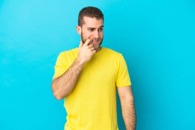 Genç yakışıklı beyaz adam mavi arka planda izole edilmiş gergin ve korkmuş.