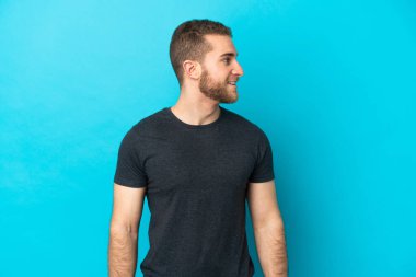 Mavi arka planda soyutlanmış yakışıklı beyaz bir adam.