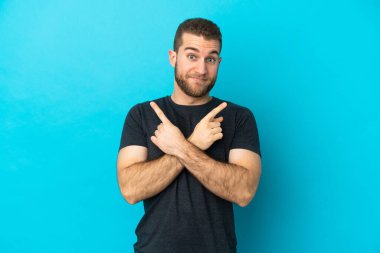 Mavi arka planda izole edilmiş yakışıklı beyaz adam, yan taraftakilerin kuşkuları olduğunu gösteriyor.
