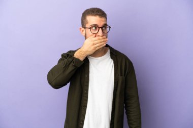 Mor arka planda izole edilmiş yakışıklı beyaz adam yan tarafa bakarken sürpriz jest yapıyor.