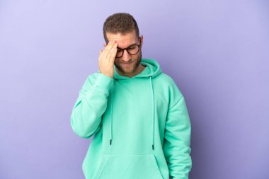 Mor arka planda başağrısı olan yakışıklı, beyaz bir adam.