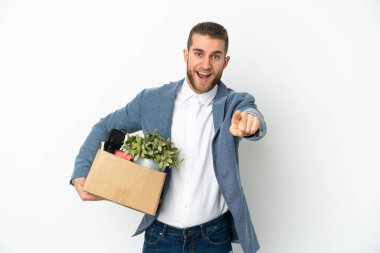 Beyaz arka planda izole edilmiş eşyalarla dolu bir kutuyu alırken genç Kafkasyalı hamle yapıyor. Şaşırmış ve ön tarafı işaret ediyor.