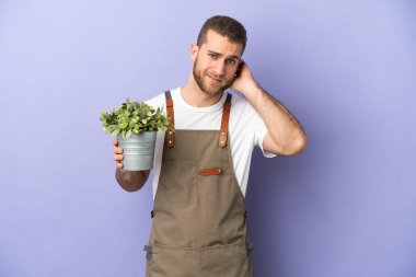 Bahçıvan beyaz adam sarı arka planda izole edilmiş bir bitki tutuyor. Şüpheleri var.