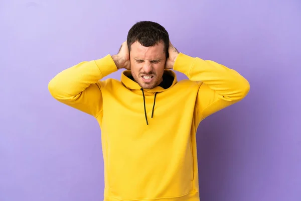 Brazilian man over isolated purple background frustrated and covering ears