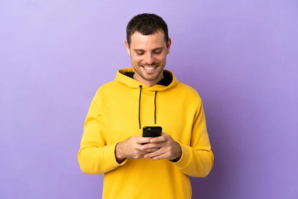 Brazilian Man Isolated Purple Background Sending Message Mobile — Stok fotoğraf