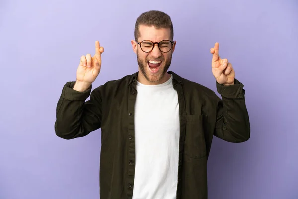 Young Handsome Caucasian Man Isolated Purple Background Fingers Crossing — Zdjęcie stockowe