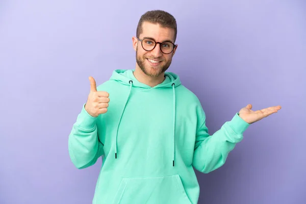 Young Handsome Caucasian Man Isolated Purple Background Holding Copyspace Imaginary — Stock fotografie