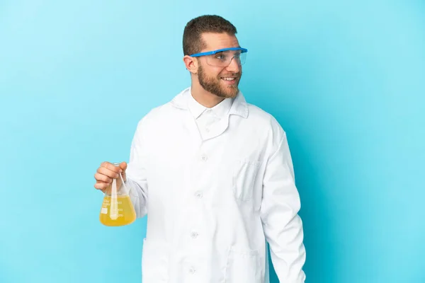 Young Caucasian Scientific Man Isolated Blue Background Looking Side Smiling — Zdjęcie stockowe