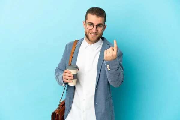 Young caucasian businessman isolated on blue background doing coming gesture