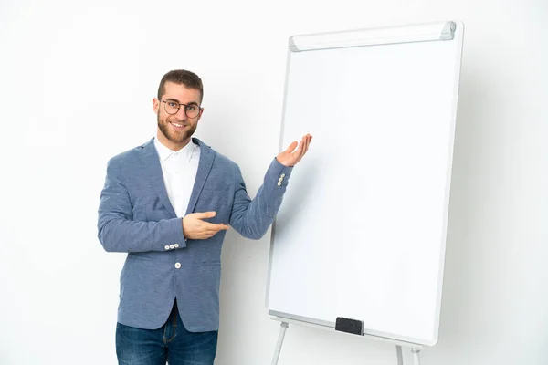 Young business woman giving a presentation on white board isolated on white background extending hands to the side for inviting to come