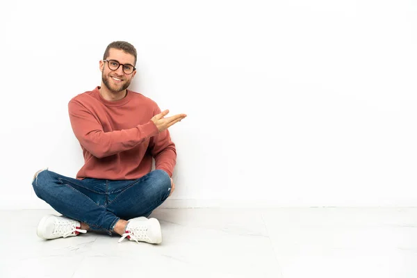 Young Handsome Man Sitting Floor Presenting Idea While Looking Smiling — Stock fotografie