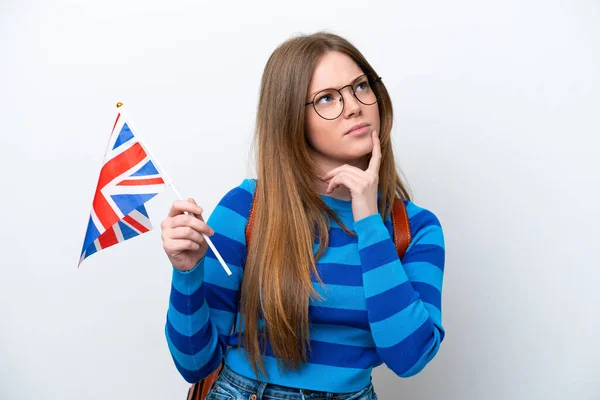 年轻的高加索女人举着一面英国国旗 背景为白色 在抬头时感到疑惑 — 图库照片