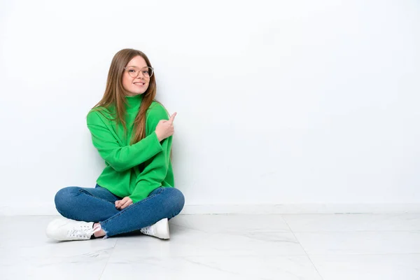 Mladá Běloška Žena Sedí Podlaze Izolované Bílém Pozadí Ukazuje Zpět — Stock fotografie