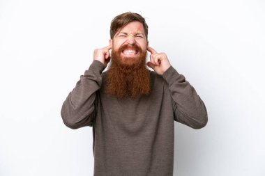 Beyaz arka planda sakallı kızıl saçlı adam hayal kırıklığına uğramış ve kulaklarını kapatmış.