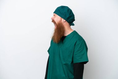 Yeşil üniformalı cerrah kızıl saçlı adam, beyaz arka planda izole edilmiş. Yan pozisyonda gülüyor.