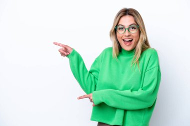 Beyaz arka planda izole edilmiş genç Uruguaylı kadın şaşırmış ve işaret ediyor.