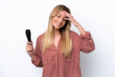 Şarkıcı Uruguaylı kadın beyaz arka planda izole edilmiş bir mikrofonu kaldırıp gülüyor.