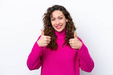 Beyaz arka planda izole edilmiş beyaz bir kadın. Baş parmakları havada ve gülümsüyor.