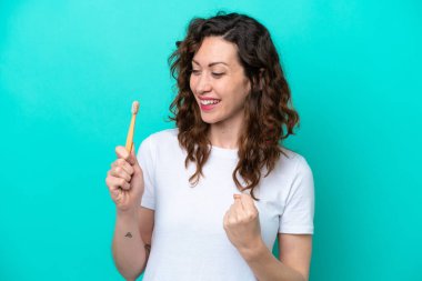 Mavi arka planda dişlerini fırçalayan beyaz bir kadın zaferi kutluyor.