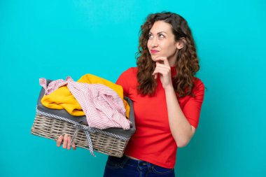 Mavi arka planda, çamaşır sepetini tutan beyaz bir kadın var.