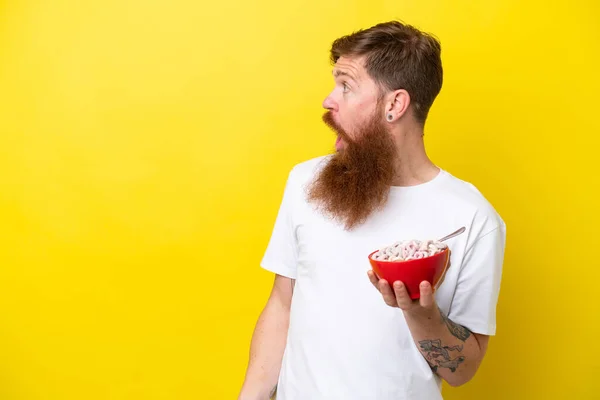 Roodharige Man Met Baard Eet Een Kom Granen Geïsoleerd Gele — Stockfoto