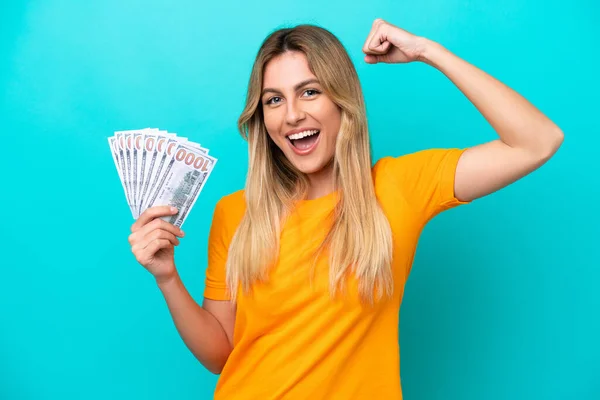 Young Uruguayan Woman Taking Lot Money Isolated Blue Background Doing — стоковое фото