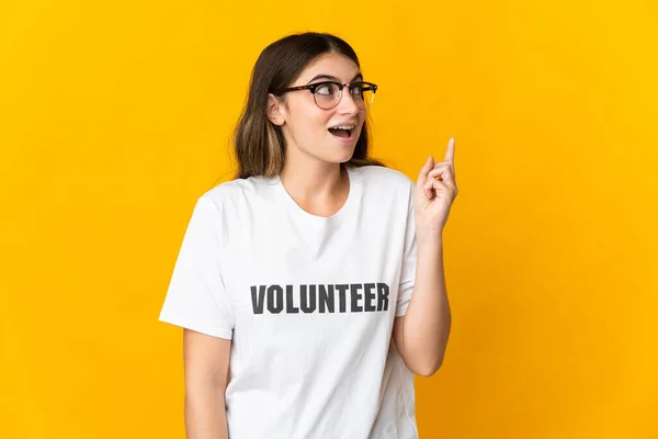 Joven Voluntaria Aislada Sobre Fondo Amarillo Pensando Una Idea Apuntando — Foto de Stock