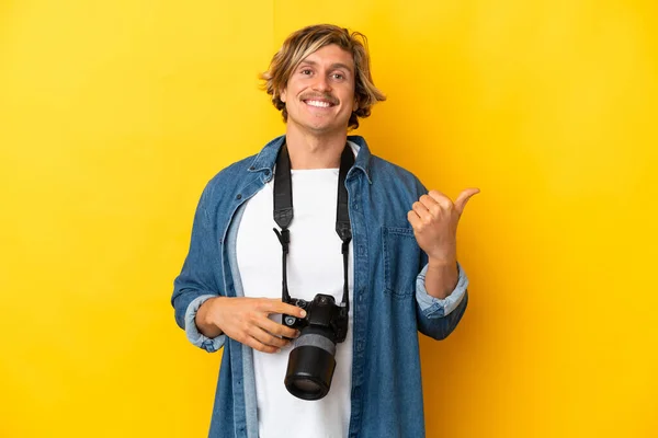 Jonge Fotograaf Man Geïsoleerd Gele Achtergrond Wijzend Naar Zijkant Een — Stockfoto