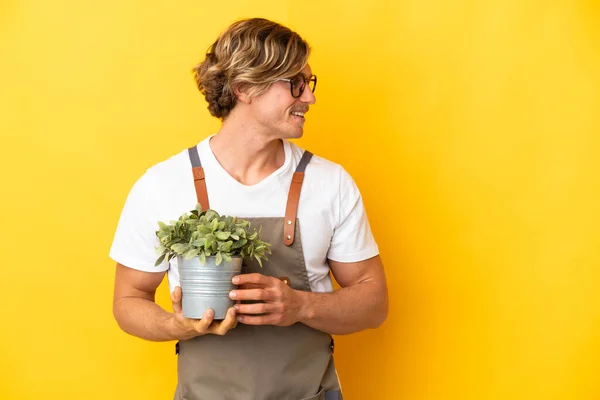 Gärtner Blonde Mann Hält Eine Pflanze Isoliert Auf Gelbem Hintergrund — Stockfoto