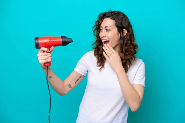 Young Caucasian Woman Holding Hairdryer Isolated Blue Background Surprise Shocked — ストック写真