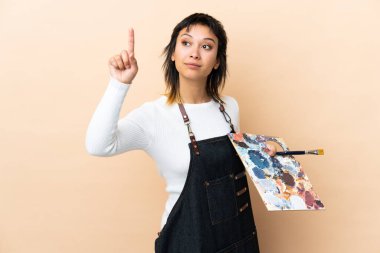 Arkaplanda bir palet tutan genç sanatçı şeffaf ekrana dokunuyor.