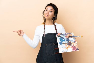 İzole edilmiş arka plan üzerinde palet tutan genç sanatçı, yan kesimlerin şüphelerini işaret ediyor.