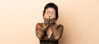 Hintli kadın bej arka planda izole edilmiş gözleri elleriyle kapatıyor