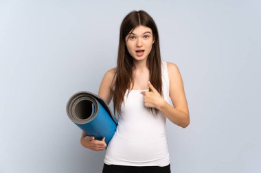 Ukraynalı genç sporcu kız, elinde sürpriz bir yüz ifadesi olan bir minderle yoga derslerine gidiyor.