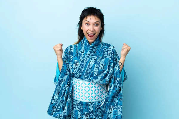 Young Woman Wearing Kimono Isolated Blue Background Celebrating Victory Winner — стоковое фото