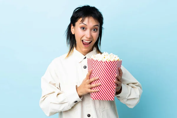 Young Uruguayan Woman Isolated Blue Background Holding Big Bucket Popcorns — Stock Photo, Image