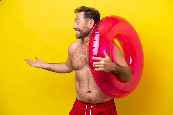 Middelbare Leeftijd Kaukasische Man Houden Opblaasbare Donut Geïsoleerd Gele Achtergrond — Stockfoto