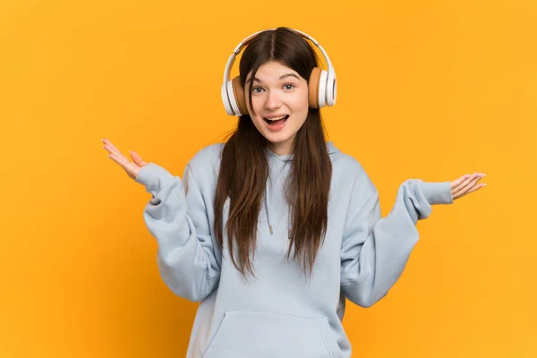 Joven Ucraniana Aislada Sobre Fondo Amarillo Sorprendida Escuchando Música —  Fotos de Stock