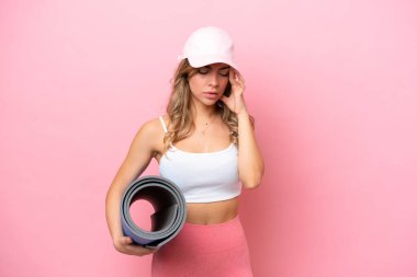 Genç sporcu kadın yoga derslerine giderken elinde baş ağrısı olan bir minder tutuyor.