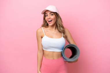 Genç sporcu kadın, elinde sürpriz bir yüz ifadesi olan bir minder tutarken yoga derslerine gidiyor.