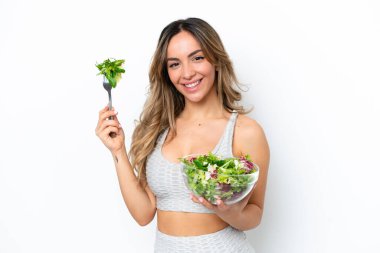 Beyaz arka planda izole edilmiş beyaz bir kadın elinde mutlu bir ifadeyle bir kase salata tutuyor.
