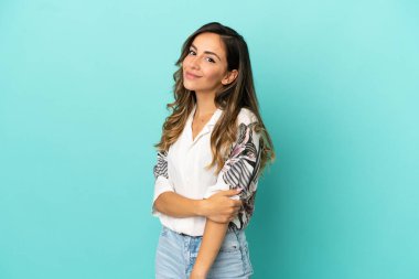 Genç bir kadın mavi arka planda gülüyor.