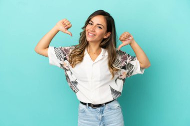 Soyutlanmış mavi arka plan gururlu ve kendini beğenmiş genç kadın.