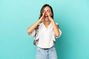 İzole mavi arka plan üzerinde genç kadın çığlık ve bir şey duyurdu