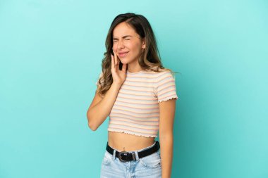 Diş ağrısı ile izole mavi arka plan üzerinde genç kadın