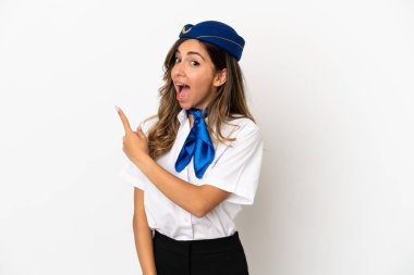 İzole edilmiş beyaz arka plan üzerinde uçak hostesi şaşırmış ve işaret ediyor.