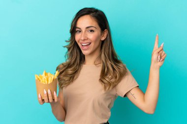 Kızarmış cipsleri izole edilmiş arka planda tutan genç bir kadın en iyinin işareti olarak parmağını kaldırıyor.